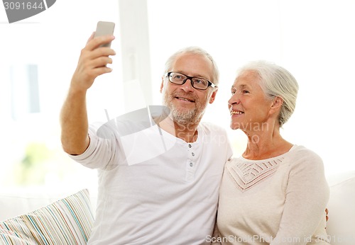 Image of happy senior couple with smartphone at home