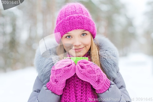 Image of smiling young woman with cup in winter forest