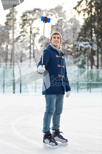 Image of happy young man with smartphone on ice rink