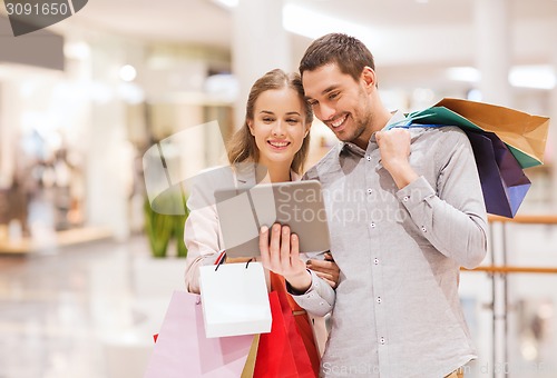 Image of couple with tablet pc and shopping bags in mall