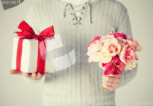 Image of man holding bouquet of flowers and gift box