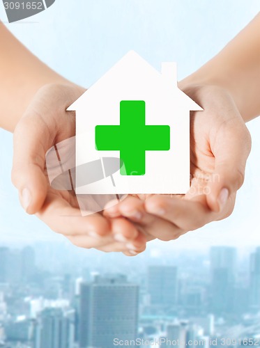 Image of hands holding paper house with green cross