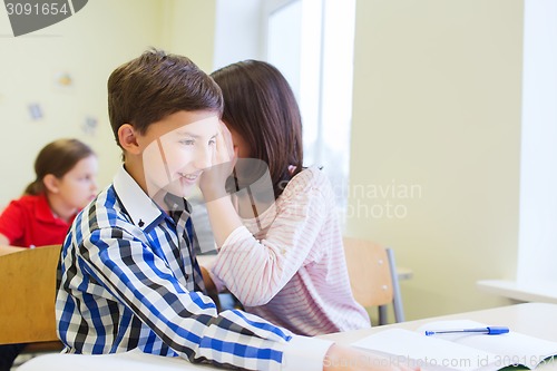 Image of smiling schoolgirl whispering to classmate ear