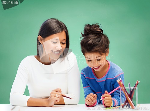 Image of happy teacher and little school girl drawing