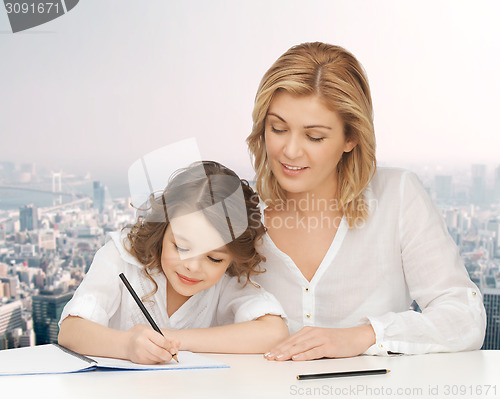 Image of happy mother and daughter writing in notebook