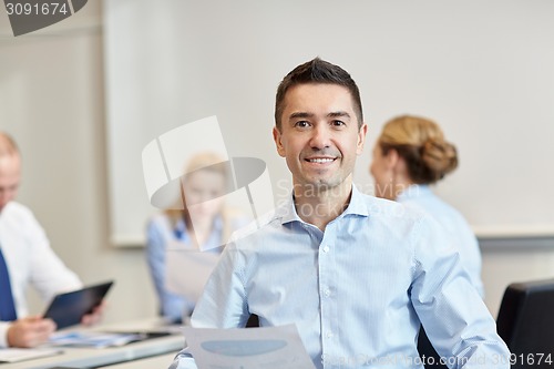 Image of smiling group of businesspeople meeting in office