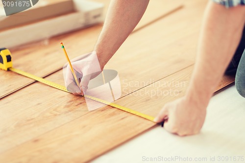 Image of close up of male hands measuring wood flooring