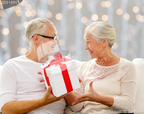 Image of happy senior couple with gift box at home