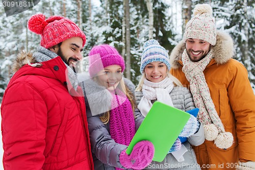 Image of smiling friends with tablet pc in winter forest