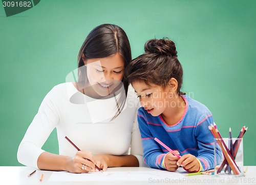 Image of happy teacher and little school girl drawing