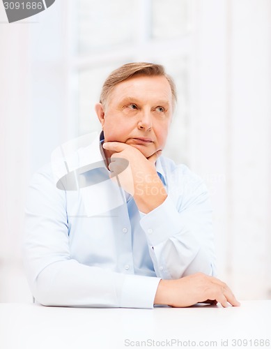 Image of stressed old man holding head at home