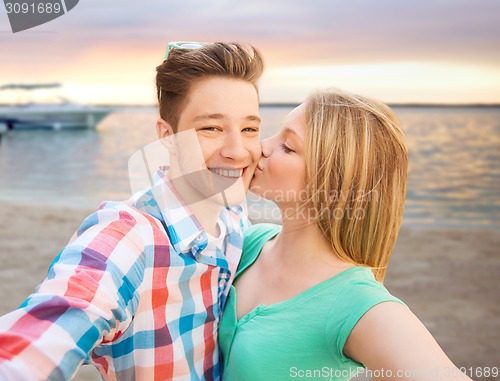 Image of happy couple taking selfie on summer beach