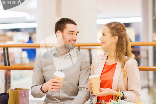 Image of happy couple with shopping bags drinking coffee