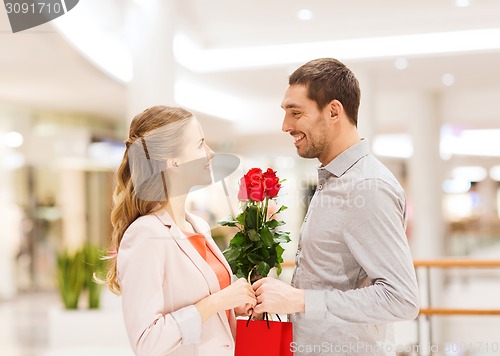 Image of happy young couple with flowers in mall