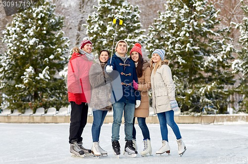 Image of happy friends with smartphone on ice skating rink