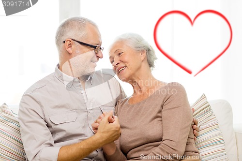 Image of happy senior couple hugging on sofa at home