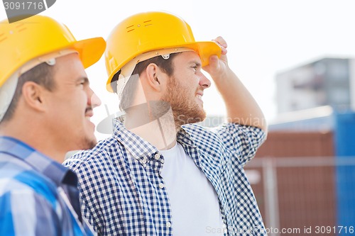 Image of group of smiling builders in hardhats outdoors