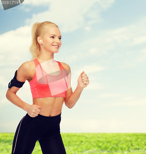 Image of sporty woman running with smartphone and earphones