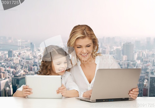 Image of mother with girl looking to laptop and tablet pc