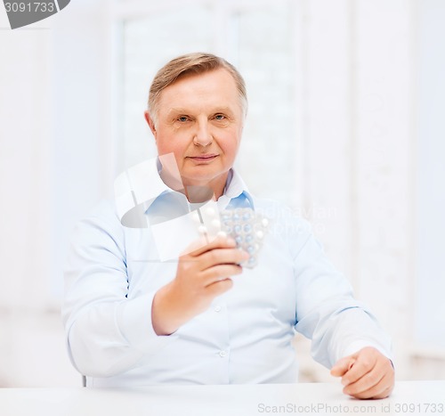 Image of old man with pack of pills