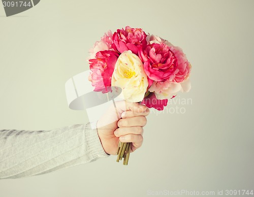 Image of man's hand giving bouquet of flowers