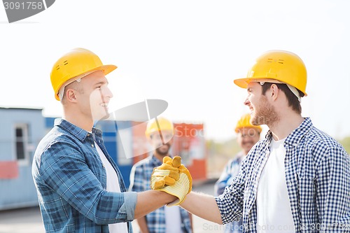 Image of group of smiling builders in hardhats outdoors