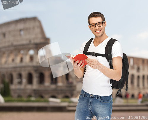 Image of happy young man with backpack and book travelling