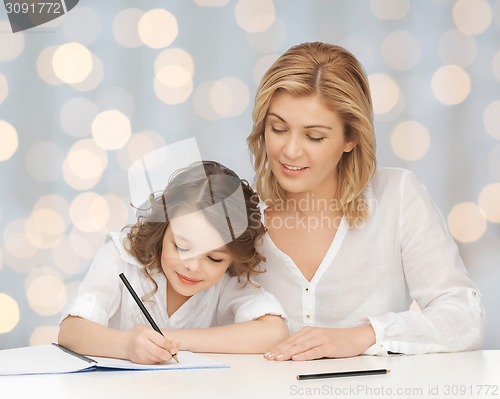 Image of happy mother and daughter writing in notebook