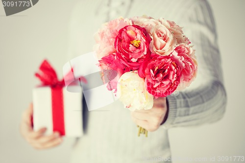 Image of man holding bouquet of flowers and gift box