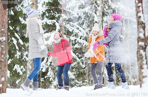 Image of group of happy friends playing snowballs in forest