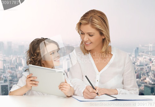 Image of woman with notebook and girl holding tablet pc 