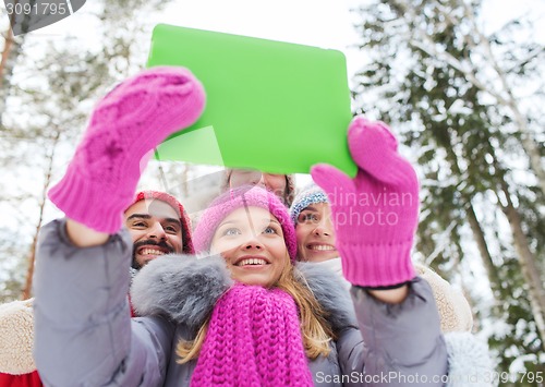 Image of smiling friends with tablet pc in winter forest