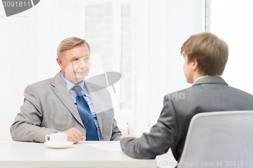 Image of older man and young man signing papers in office