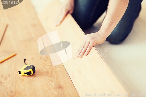 Image of close up of male hands intalling wood flooring