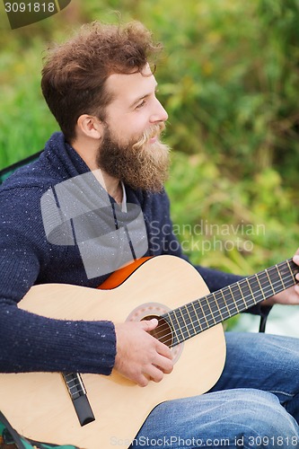 Image of smiling man playing guitar in camping