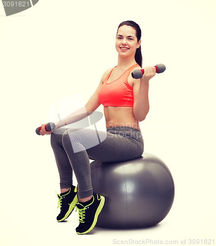 Image of teenager with dumbbells sitting on fitness ball