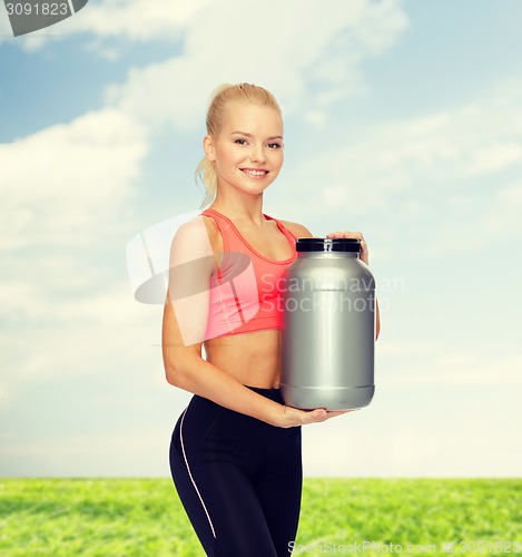 Image of smiling sporty woman with jar of protein