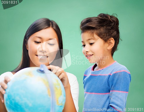 Image of happy teacher and little school girl with globe