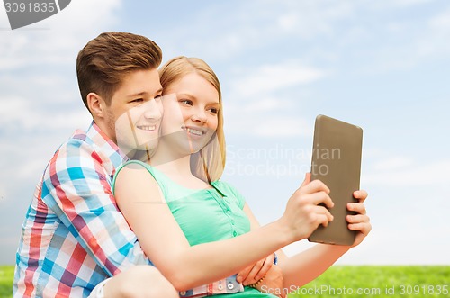 Image of happy couple with tablet pc taking selfie outdoors