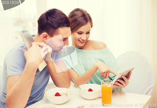 Image of smiling couple with tablet pc reading news