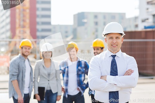 Image of group of smiling builders in hardhats outdoors