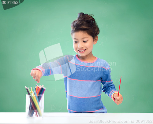 Image of happy school girl drawing with coloring pencils