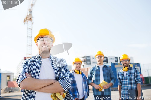 Image of group of smiling builders in hardhats outdoors