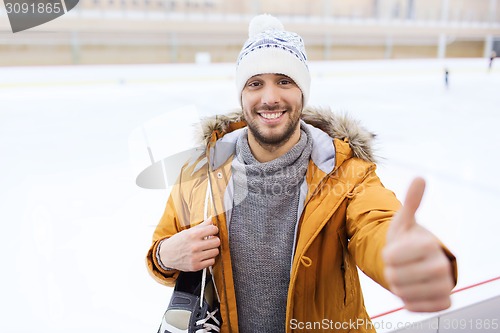 Image of happy young man showing thumbs up on skating rink