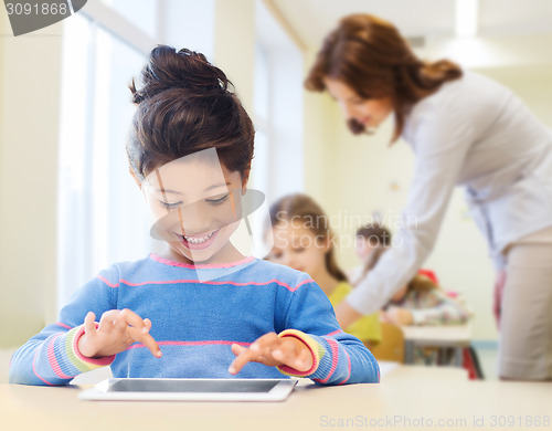 Image of little school girl with tablet pc over classroom