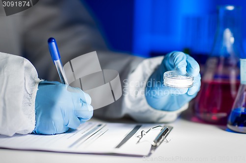 Image of close up of scientist writing test results in lab