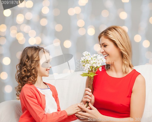 Image of happy little daughter giving flowers to her mother