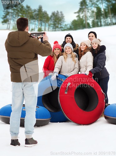 Image of group of smiling friends with snow tubes