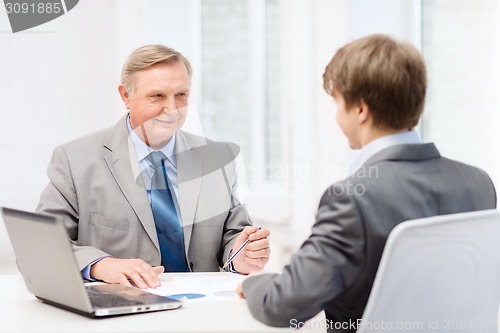 Image of older man and young man having meeting in office