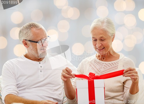 Image of happy senior couple with gift box at home